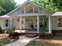 Charming home exterior featuring a covered front porch with seating and landscaped garden beds at 4172 Copeland Ter, Graham, NC 27253