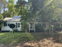 Quaint home featuring a metal roof, surrounded by mature trees and a spacious front yard at 529 Sunset Dr, Fuquay Varina, NC 27526