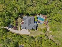 Stunning aerial view of the home with a pool, lush landscaping and surrounded by mature trees at 6824 Wood Forest Dr, Cary, NC 27519