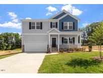 Charming two-story home with gray siding, blue accents, covered porch, and well-manicured lawn at 90 Cordoba Dr, Franklinton, NC 27525