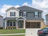 Two-story home featuring a two-car garage, a covered front porch, and a well-manicured lawn at 1120 Landen Creek Ln, Zebulon, NC 27597
