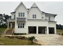A charming two-story white farmhouse with a three-car garage and manicured front yard at 1217 Azalea Garden Cir, Raleigh, NC 27603