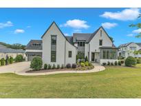 Stunning two-story home with a white brick facade, elegant dark trim, and a meticulously manicured lawn at 1633 Estate Valley Ln, Raleigh, NC 27613