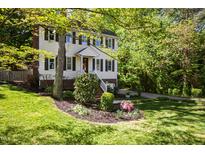 Charming two-story home with light yellow siding, black shutters, brick foundation and lush landscaping at 213 Beechtree Dr, Cary, NC 27513