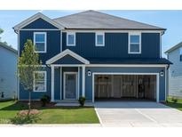 Charming two-story home with blue siding, an open garage, a manicured lawn, and decorative landscaping at 2218 Cherry Creek Rd, Haw River, NC 27258