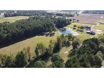 Expansive aerial view of property featuring a pond, barn, and surrounding fields and trees at 2747 Beasley, Benson, NC 27504