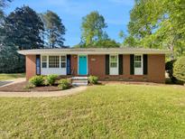 Charming brick home with a well-maintained lawn, a bright blue front door, and lush landscaping at 3504 Crofton Ct, Raleigh, NC 27604