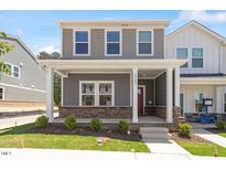Charming two-story home featuring a welcoming front porch with stylish brick accents and manicured landscaping at 3715 Rosebush Dr, Zebulon, NC 27597