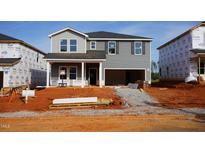 New two-story home with gray siding, an open garage, and a covered front porch under construction at 724 Deschutes Dr, Garner, NC 27529