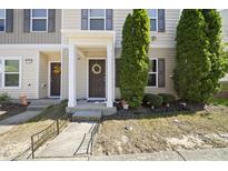 Inviting townhouse facade featuring a brown front door with wreath and charming landscaping with trees on a sunny day at 8520 Quarton Dr, Raleigh, NC 27616