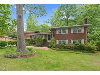 Charming two-story brick home featuring a landscaped front yard with mature trees and manicured shrubbery at 905 Cindy St, Cary, NC 27511