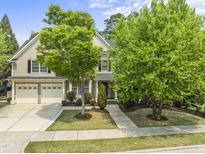Charming two-story home with a two car garage and landscaped front yard, including lush green trees at 909 Grogans Mill Dr, Cary, NC 27519