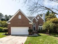 Charming brick home with a well-manicured lawn, two-car garage and mature tree in the front yard at 117 Whitehaven Ln, Cary, NC 27519