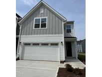 Charming two-story home showcasing a white garage door, grey siding, and modern architectural details at 1214 Tredenham Way, Durham, NC 27703
