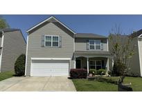 Charming two-story home with gray siding, a front-facing garage, manicured lawn, and mature landscaping at 123 Charndon Way, Fuquay Varina, NC 27526