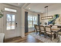 Elegant dining room with modern light fixture, stylish rug, and ample natural light from a large window at 125 Verona Villa Dr, Burlington, NC 27215