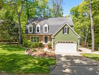 Charming home with a brick facade, green siding, and lush landscaping at 1408 Bridgeport Dr, Raleigh, NC 27615
