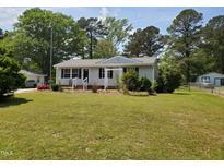 Charming single-story home with a well-manicured lawn, mature trees, and a welcoming front porch at 206 Lane Of Tristram, Garner, NC 27529