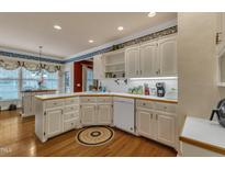 Bright kitchen features white cabinets, breakfast bar, and hardwood floors at 208 E Harrington Ave, Broadway, NC 27505