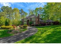 Beautiful brick home with a circular driveway, lush green lawn and manicured landscaping at 3203 Cameron Dr, Henderson, NC 27536
