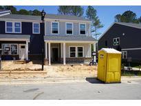 New two-story home with light gray exterior, brick accents, and visible construction activity at 3711 Rosebush Dr, Zebulon, NC 27597