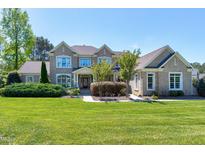 Stunning brick home featuring lush landscaping and a manicured lawn on a sunny day at 4001 Belmont Forest Way, Raleigh, NC 27606