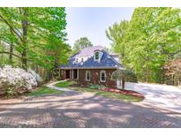 Charming brick home with lush landscaping, mature trees, and a brick paver driveway at 5504 Spring Bluffs Ln, Raleigh, NC 27606
