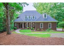 Charming brick home with a well-manicured lawn, mature trees, and inviting front entrance at 5504 Spring Bluffs Ln, Raleigh, NC 27606