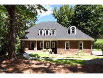 Charming brick home with arched windows and a manicured lawn, surrounded by mature trees at 5504 Spring Bluffs Ln, Raleigh, NC 27606