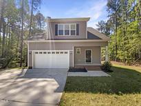 Charming two-story home featuring a gray facade, white garage door, and landscaped front yard at 6245 Reagan Ln, Wake Forest, NC 27587