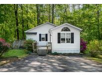 Charming cottage-style home with white siding, black shutters, and mature landscaping at 107 Piquot Dr, Louisburg, NC 27549