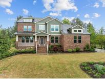 Beautiful two-story brick home with a green facade, a porch, and a professionally landscaped front yard at 1104 Covered Bridge Trl, Chapel Hill, NC 27517