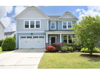 Charming two-story home featuring a well-manicured lawn and a two-car garage, all under a sunny blue sky at 1209 Redwood Valley Ln, Knightdale, NC 27545