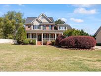 Charming two-story brick home featuring a welcoming front porch and lush landscaping at 192 Crestdale Dr, Clayton, NC 27520