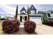 Charming two-story home featuring a white garage door, blue siding, manicured shrubs, and a welcoming front entrance at 1925 Bright Kannon Way, Wendell, NC 27591