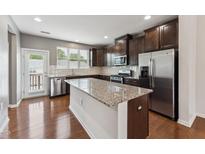 A kitchen featuring stainless steel appliances, granite countertops, and dark wood cabinets at 2027 Hayes Ln, Holly Springs, NC 27540