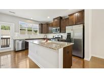 Modern kitchen features granite countertops, stainless steel appliances, and ample cabinet space at 2027 Hayes Ln, Holly Springs, NC 27540