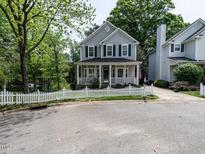 Charming two-story home featuring a white picket fence, covered porch, and landscaped yard with mature trees at 207 Reedhaven Dr, Cary, NC 27513