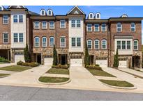 Townhome exterior with brick and stone accents, manicured lawns, driveways, and attached one car garages at 212 Allister Dr, Raleigh, NC 27609