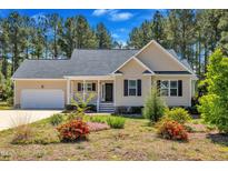Charming single-story home with a well-manicured lawn and attached garage and welcoming front porch at 215 Oxfordshire Dr, Fuquay Varina, NC 27526