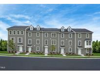 View of new construction townhomes with gray siding and white doors, sidewalk and lush lawn at 2303 Pitchfork Ln, Durham, NC 27713