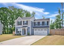 Charming two-story home featuring a two-car garage, manicured lawn, and classic architectural details at 390 Hunting Wood Dr, Angier, NC 27501