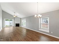 Bright living room featuring wood floors, fireplace, and sliding door to the outside at 5000 Avenida Del Sol Dr, Raleigh, NC 27616