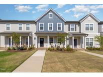 Inviting townhome exterior features a landscaped yard and charming front porch at 717 Silo Park Dr, Wake Forest, NC 27587