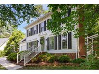 Charming two-story home featuring white siding, black shutters, and a brick staircase leading to the front door at 1002 Springmill Ct, Apex, NC 27502