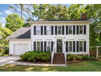 Charming two-story home with white siding, black shutters, landscaped yard, and brick stairs leading to the front door at 1002 Springmill Ct, Apex, NC 27502