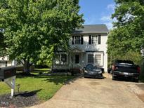 Traditional two-story home with a well-manicured lawn, mature trees, and a private driveway at 1211 Odyssey Dr, Durham, NC 27713