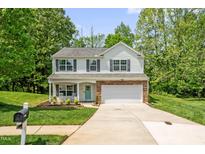 Charming two-story home features a well-manicured lawn, attached two-car garage, and inviting front porch at 1305 Montreux Ct, Mebane, NC 27302