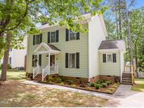 Charming two-story home featuring a well-maintained lawn, garden beds, and a welcoming front porch with a white railing at 200 Wood Hollow Dr, Cary, NC 27513