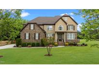 Attractive two-story home featuring stone accents, manicured lawn, and inviting front entrance at 2053 Monthaven Dr, Wake Forest, NC 27587
